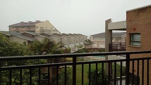 A residential building with a balcony, a brick wall, and a white fence. - Labori Ballito 3-bedroom Apartments WBT Rentals (Ballito)
