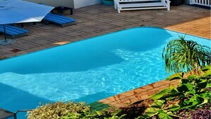 A swimming pool with a white bench and lounge chairs, surrounded by potted plants and a tiled patio. - Kridzil Holiday Flats, Margate, 1-bed Wbt Rentals (Margate)