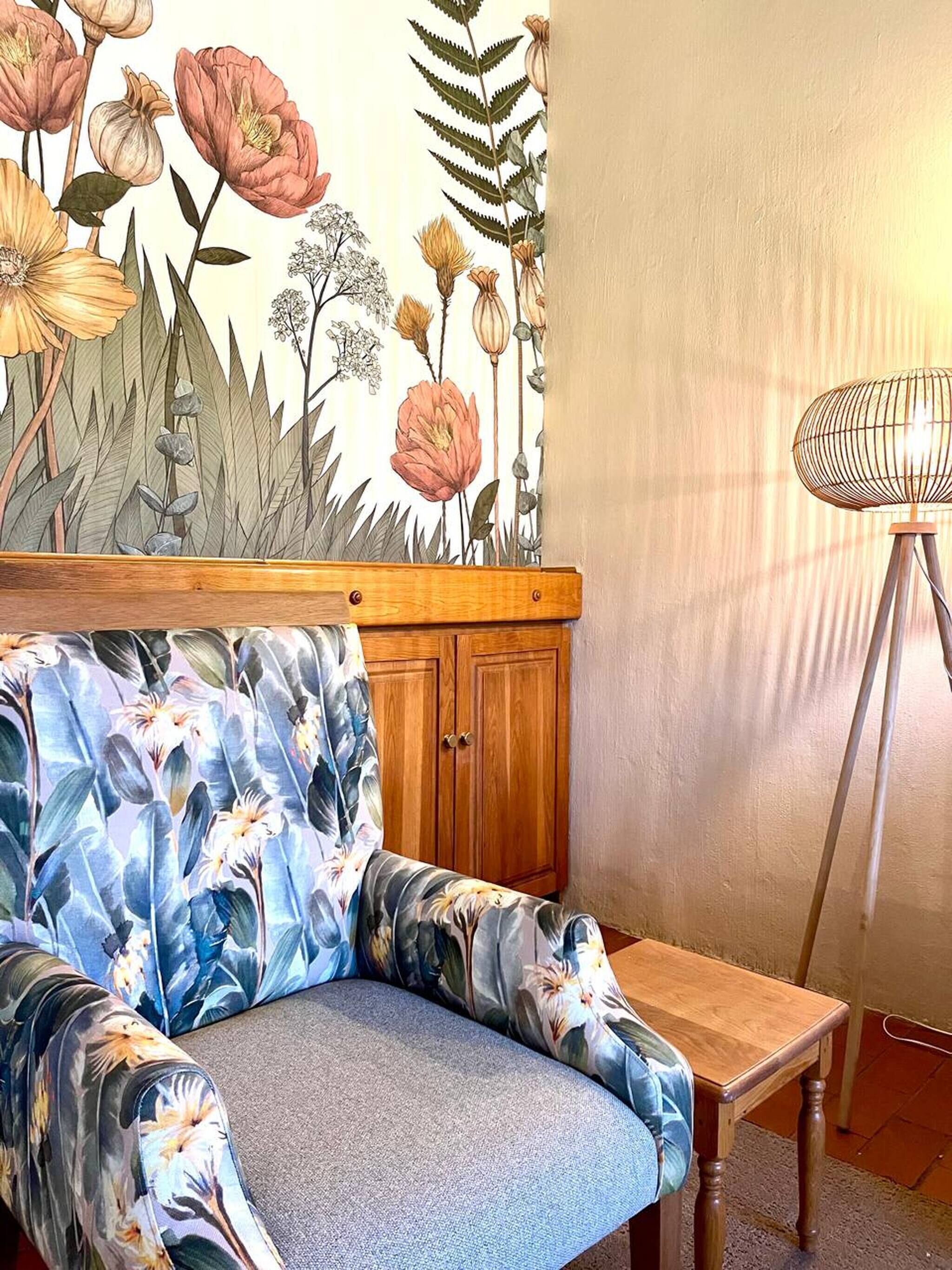 Une pièce avec un canapé à motifs floraux, un meuble en bois et un lampadaire.