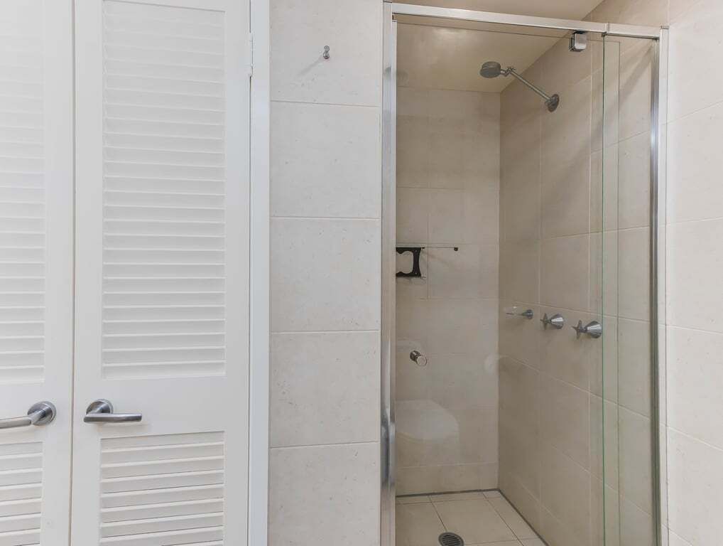 Cabina de dutxa amb vidre, plat de dutxa manual, penjador de tovalloles i vàter.