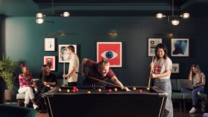 A pool table in a room with green walls, framed artwork, and a potted plant. - Student Only Sky Plaza (Leeds)