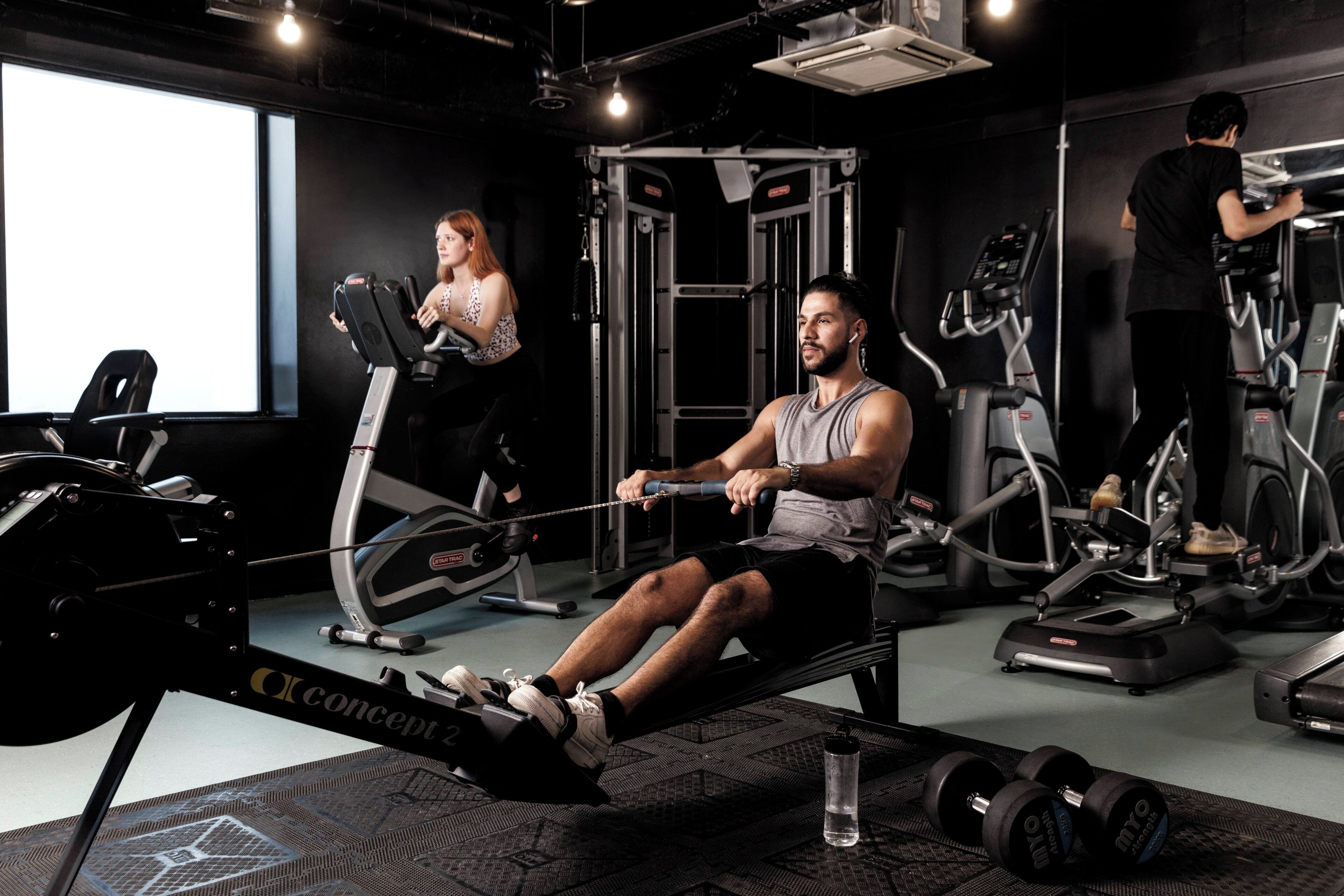 A gym with exercise equipment, a large window, and a water bottle on the floor.