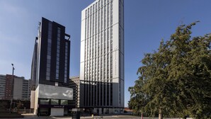 A modern high-rise building with a prominent glass facade, a visible sign for 'Premier Inn,' and a tree to the right. - Student Only Sky Plaza (Leeds)