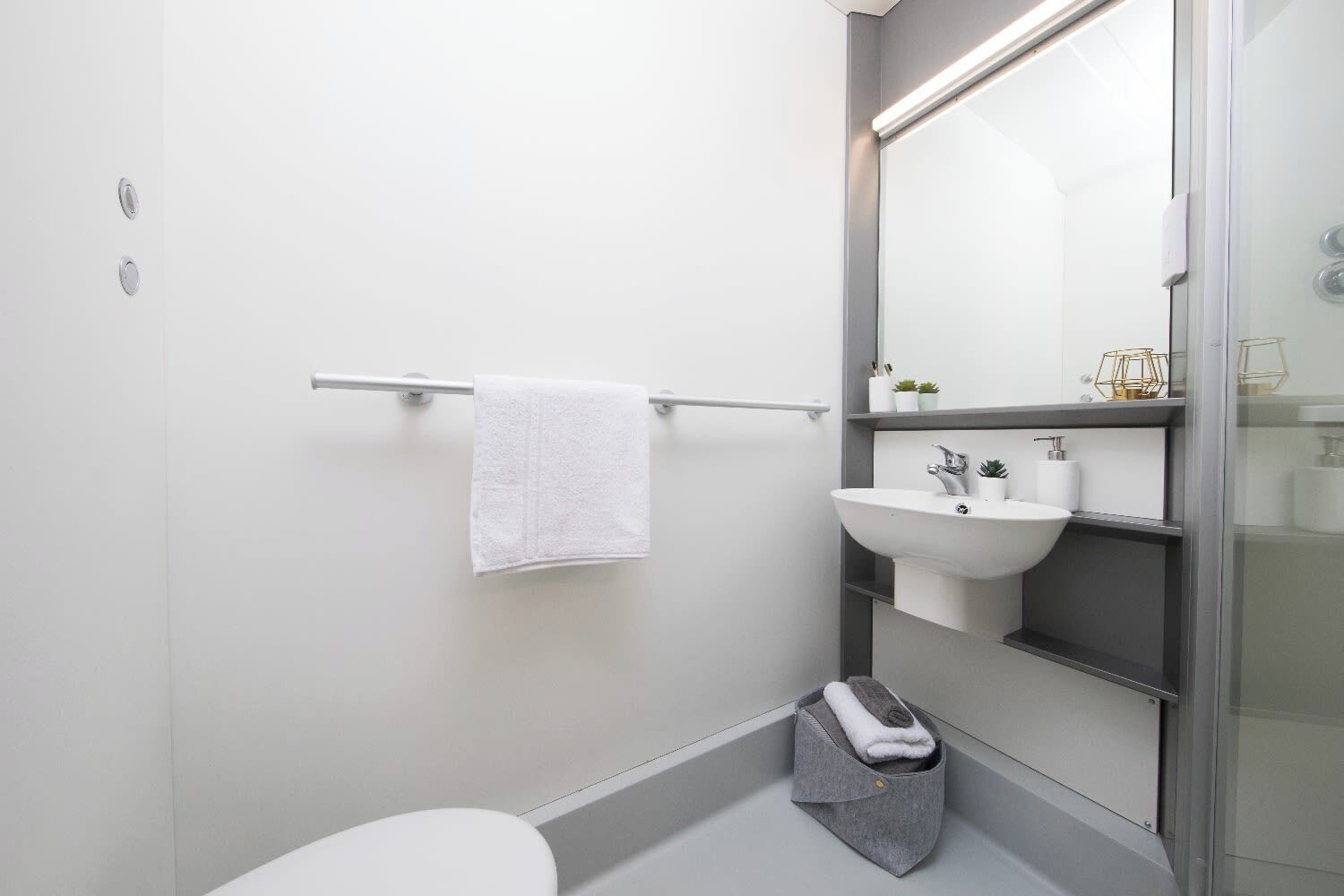 A modern bathroom with a white sink, a towel rack, and a glass shower enclosure.