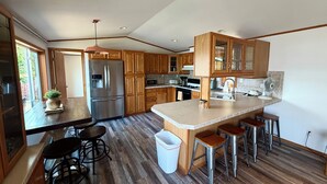 Una cocina moderna con armarios de madera, un refrigerador de acero inoxidable, horno empotrado y una isla grande con taburetes.