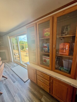 A kitchen with wooden cabinets, a glass-fronted display case, and a view of the outdoors.