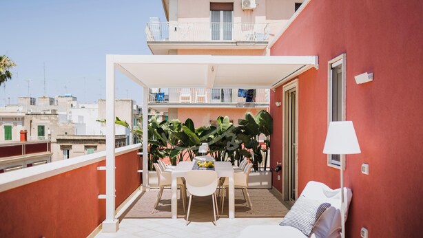 A balcony with a dining table, chairs, and a sofa. There are plants and a lamp. - TD Terrazza Giulia Monopoli City Center (Monopoli)