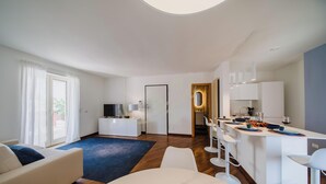 A modern living room with a sofa, a TV, and a dining area with chairs and a table. - TD Terrazza Giulia Monopoli City Center (Monopoli)