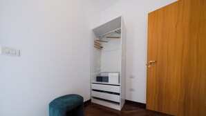 A walk-in closet with hanging space and drawers, a wooden door, and a small chair. - TD Terrazza Giulia Monopoli City Center (Monopoli)