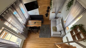 Un interior moderno con comedor, sofá, escalera y ventanas amplias.