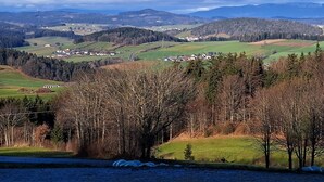 Un paisaje rural con colinas ondulantes, casas dispersas y cielo despejado.