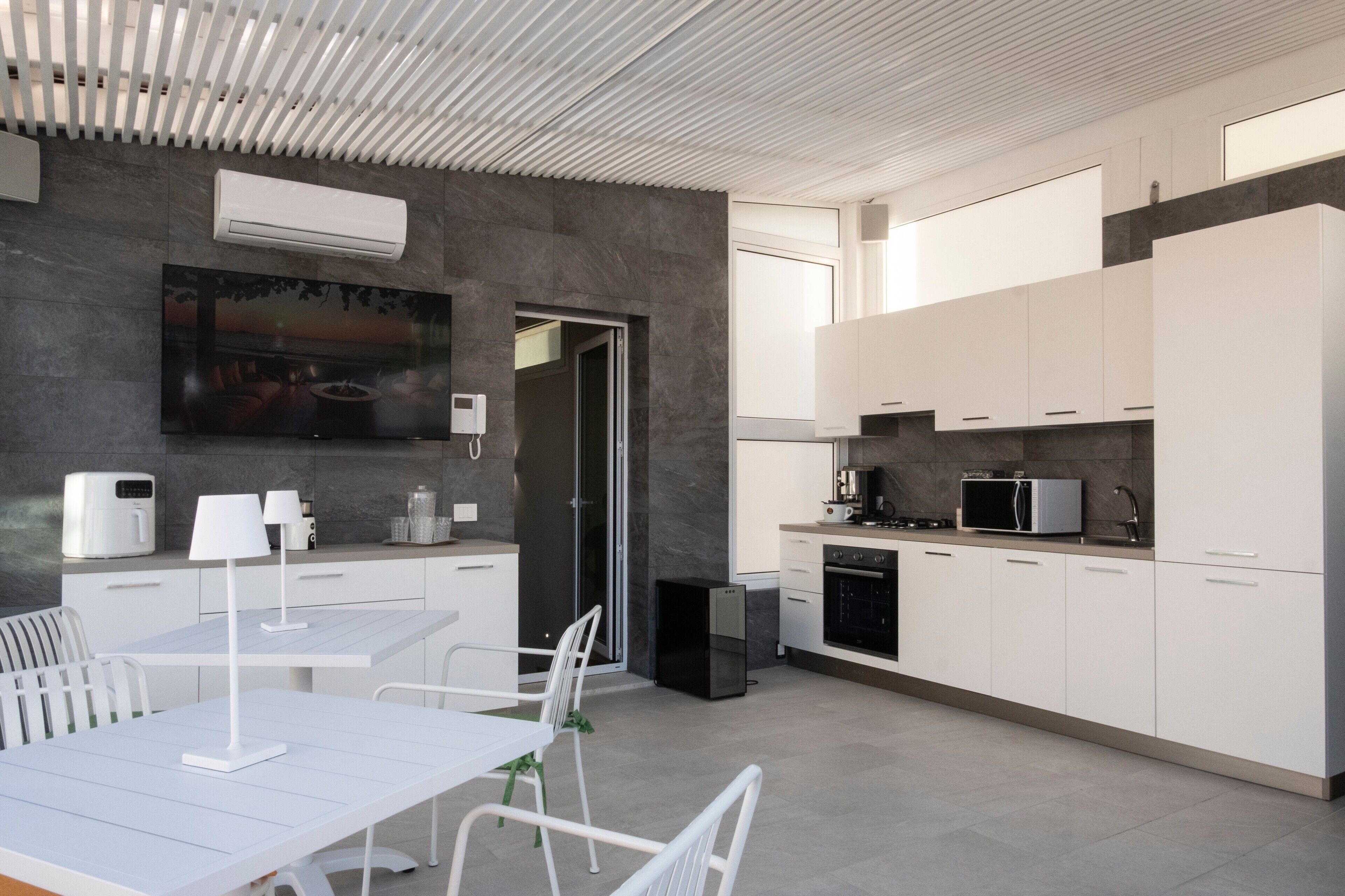 Une cuisine moderne avec des meubles blancs, un coin repas comprenant une table et des chaises, et un plafond au design épuré.