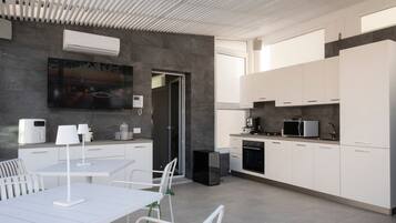 Une cuisine moderne avec des meubles blancs, un coin repas comprenant une table et des chaises, et un plafond au design épuré.