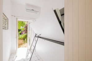 A room with a white wall, a door leading to a garden, and a ladder leaning against the wall. - Villa Cristina | Panoramic ocean view, main level with no steps, Praiano (Praiano)