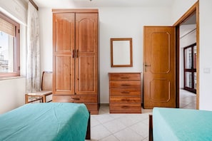 Een slaapkamer met twee bedden, een kledingkast, een dressoir en een spiegel.