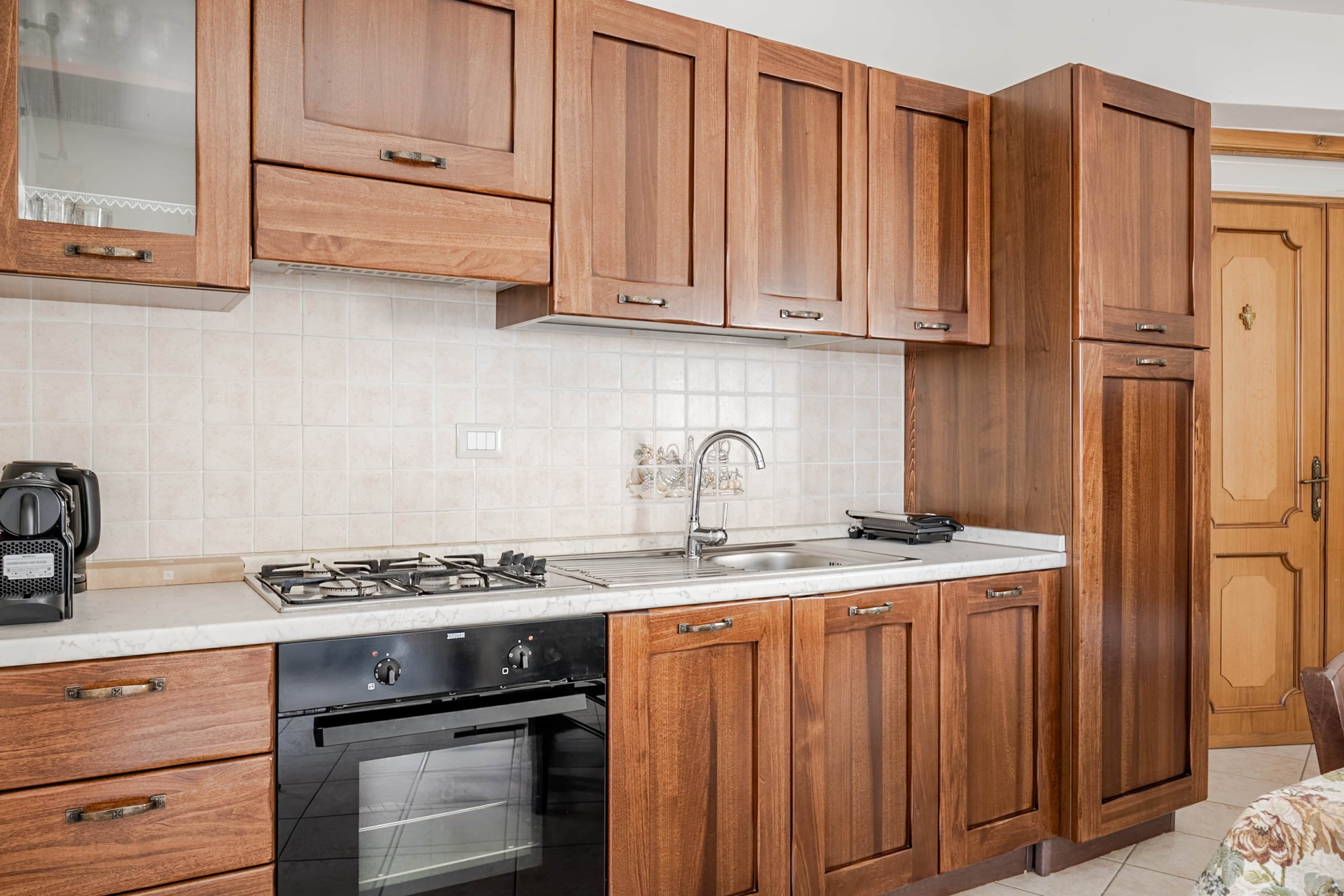 Una cucina con mobili in legno, un fornello a gas, un lavandino e una macchina per il caffè.