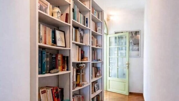 Un couloir avec une bibliothèque, un plancher en bois et une porte.