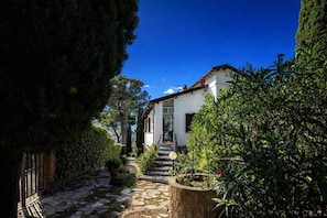 A pathway leading to a white building with a red roof, surrounded by greenery and a clear blue sky. - Villa Belvedere | Lake Bolsena View (Montefiascone)