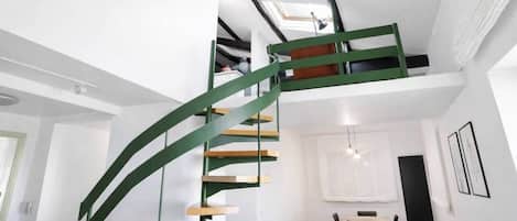 Un intérieur moderne avec un escalier en colimaçon, un coin repas et un salon.