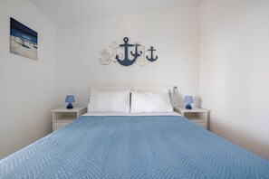 Ein ordentlich gemachtes Bett mit einer blauen Steppdecke, weißen Kissen und zwei Nachttischen mit Lampen.