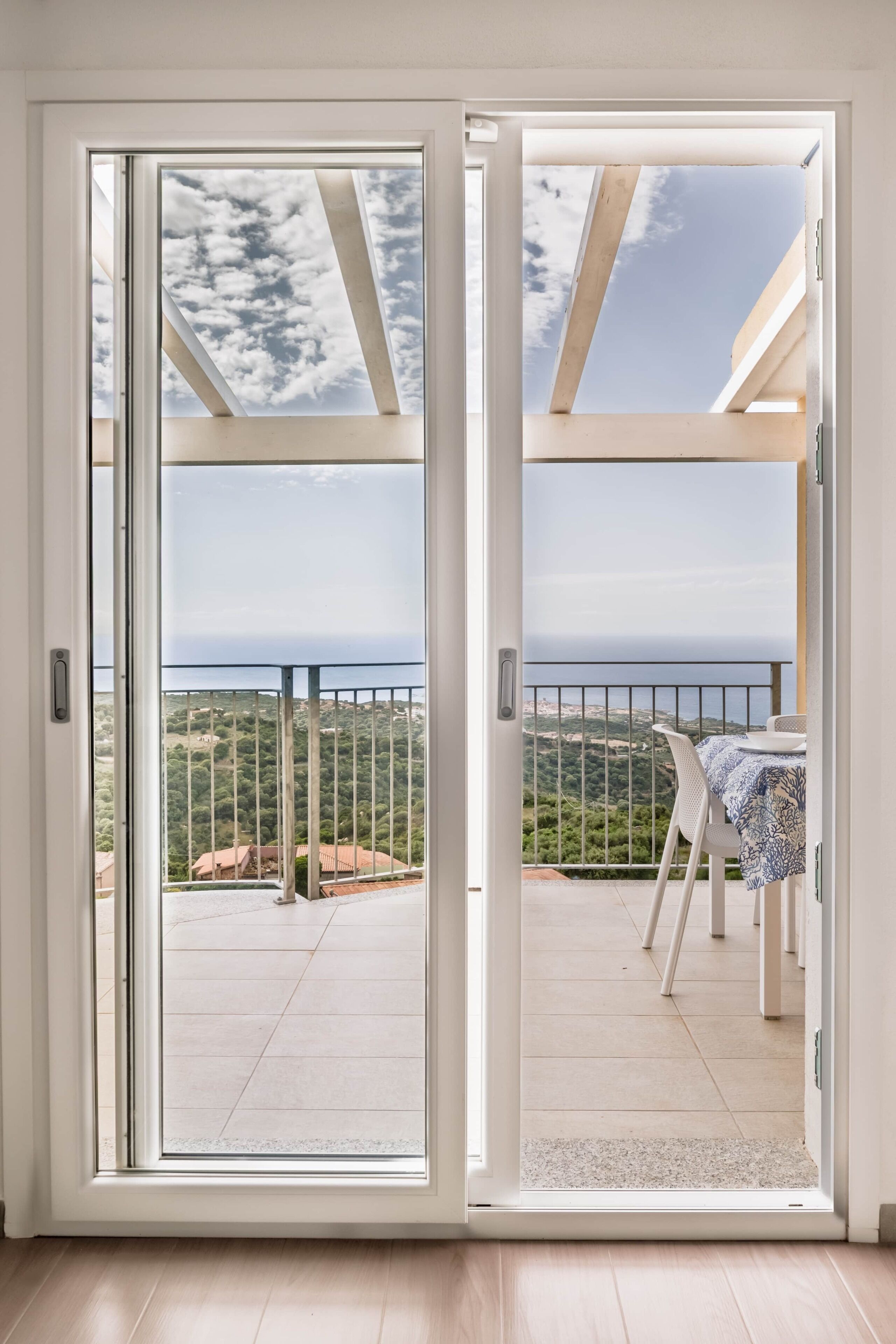 A room with a sliding glass door leading to an outdoor balcony with a table and chairs.