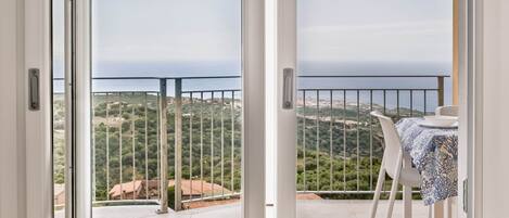 A room with a sliding glass door leading to an outdoor balcony with a table and chairs.