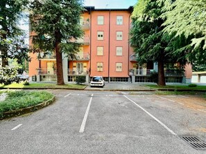 A multi-story building with a parking lot in front. - Design House | Parking,Terrace (Bergamo)