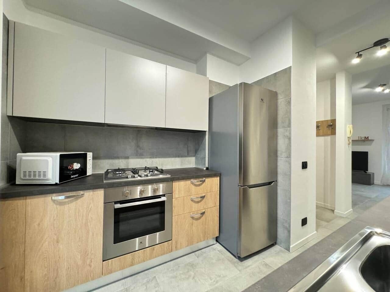 A modern kitchen with stainless steel appliances, wooden cabinets, and a grey countertop.