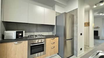 Una cucina moderna con elettrodomestici in acciaio inossidabile, mobili in legno e un piano di lavoro grigio.