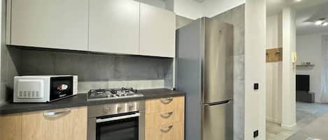 A modern kitchen with stainless steel appliances, wooden cabinets, and a grey countertop.
