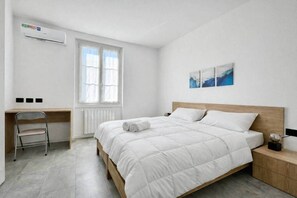 A bedroom with a bed, a desk, a chair, a radiator, and a window. - Design House | Parking,Terrace (Bergamo)