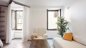 Una habitación con una mesa de madera, un sofá blanco, una silla y una planta.