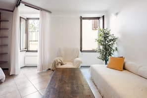 Een kamer met een houten tafel, een witte bank, een stoel en een plant.