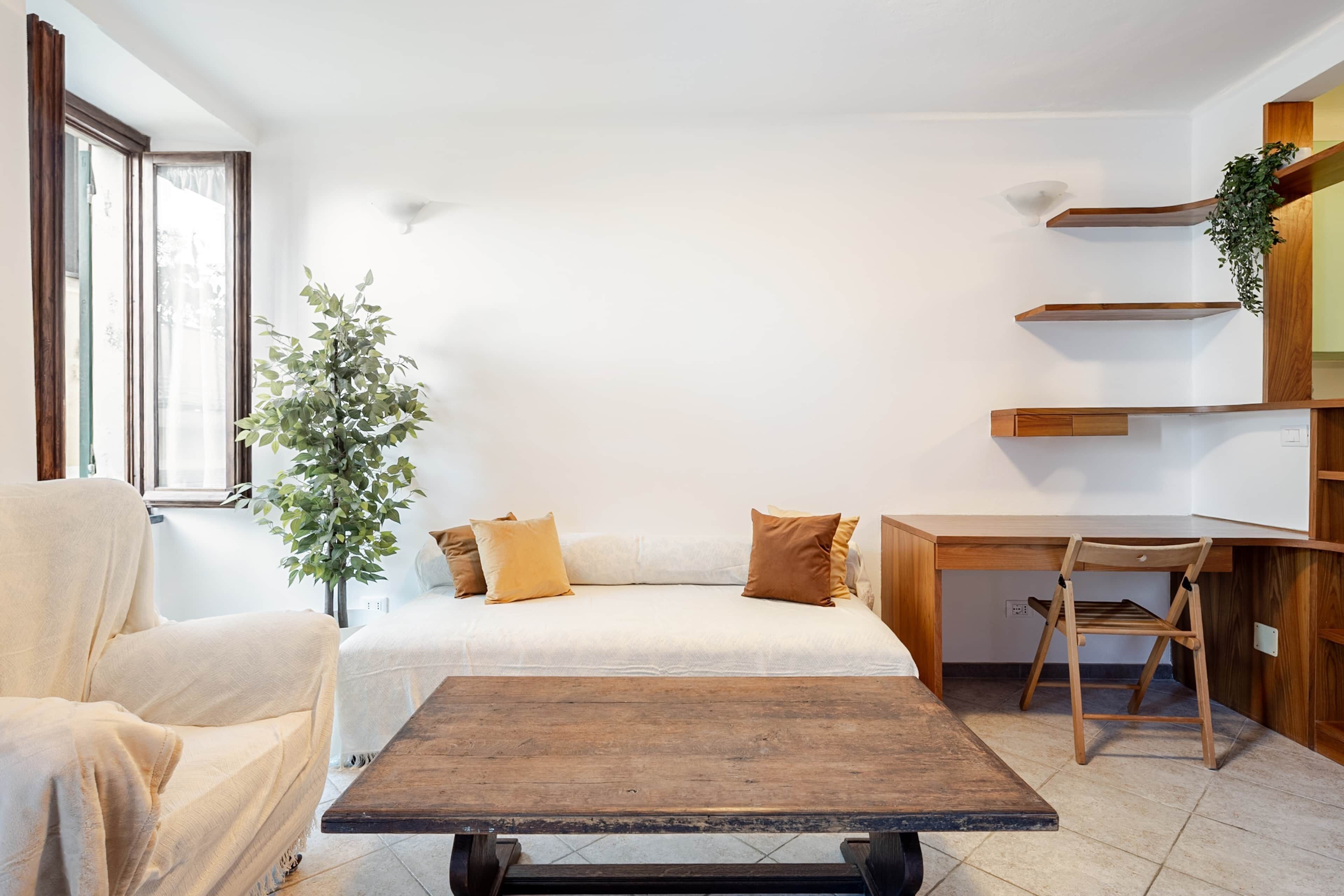Una habitación con cama, una silla, una mesa y una planta.