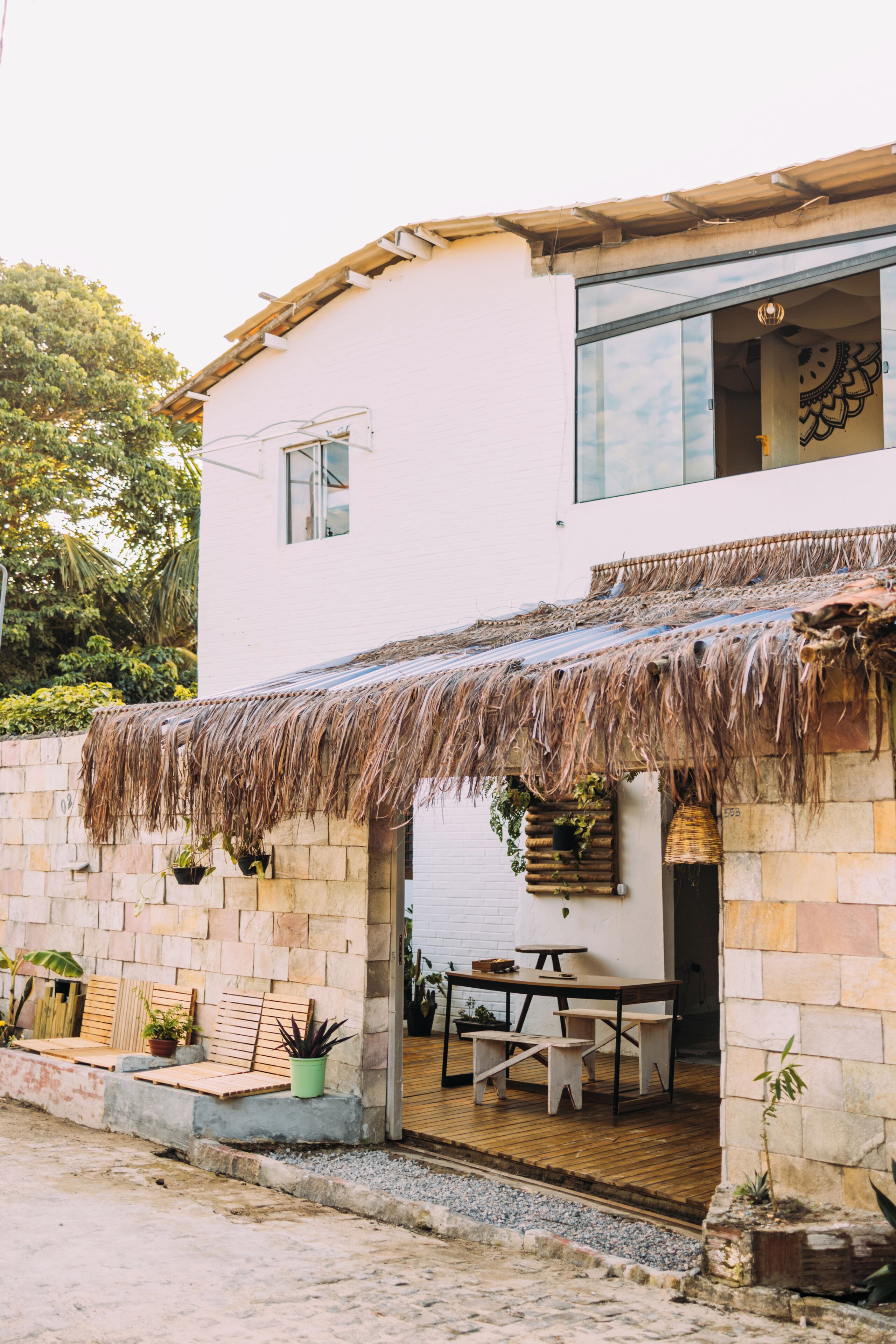 Uma casa moderna com telhado de palha, paredes de pedra e deck de madeira.