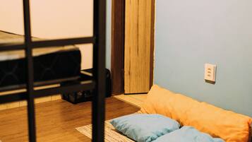 A room with a bunk bed, a door, a wall with framed pictures, a power outlet, and a rug on the floor.