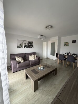 Ein modernes Wohnzimmer mit Sofa, Couchtisch und Essbereich.