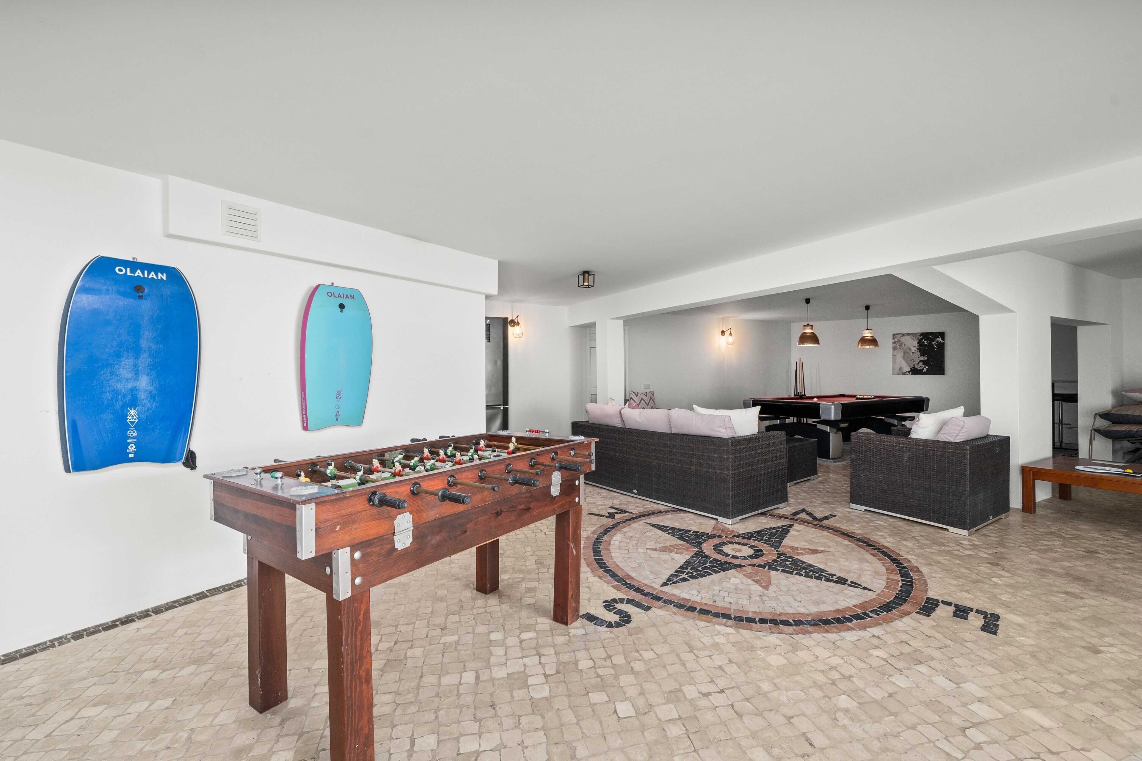 Ein großzügiger Innenbereich mit Tischfußball, Billardtisch und einer gemütlichen Sitzecke mit Sofas und Couchtisch.