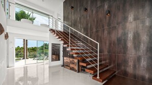 A modern interior with a staircase, a glass door leading outside, and a wall with a textured finish. - Villa Catalina with Infinity Pool and Sea View (Armação de Pêra)