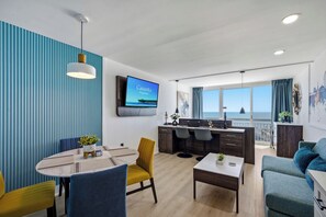 Un salon moderne doté d’un téléviseur, d’un coin repas et offrant une vue sur la mer.