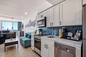 A modern kitchen with white cabinets, a built-in oven, and a microwave. - Oceanfront Pierfection by Casanita - Lux Suite (Myrtle Beach)