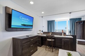 A modern kitchen with a large TV displaying 'Casanita Properties' and a pier view. - Pierfront Paradise by Casanita - Oceanfront Suite (Myrtle Beach)