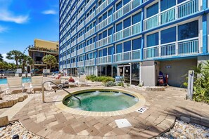 Un hotel con piscina, mobiliario exterior y un edificio con múltiples ventanas.