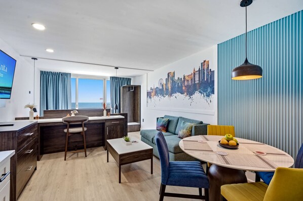 Un saló modern amb zona de menjador, cuina i una finestra gran amb cortines.