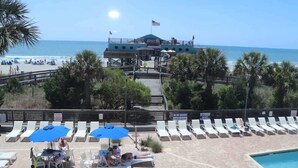 Ein Strandhotel mit Poolbereich, Liegestühlen und einem Rettungsturm.