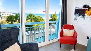 Ein Zimmer mit Blick auf einen Pool und Palmen, ein roter Sessel und ein blauer Ohrensessel.