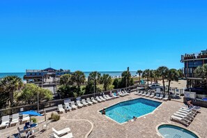 Poolbereich eines Resorts mit Liegestühlen, einem kleinen Pool und Blick auf den Strand.