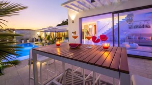Une terrasse extérieure moderne, avec une table en bois, des bougies et une piscine.