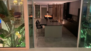 Une cuisine moderne dotée d’un îlot central, d’un coin repas avec des chaises et d’une cloison en verre.