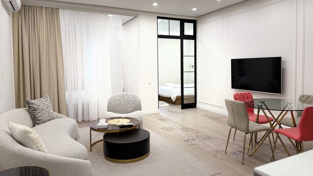 A modern living room with a sofa, round coffee table, and a TV. - Stylish 2-bedroom Apartment Next to the Republic Sqaure (Yerevan)